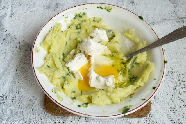 Добавляем к теплому овощному пюре мягкую рикотту или протертый творог. Вводим куриное яйцо, солим смесь по вкусу и тщательно перемешиваем массу.