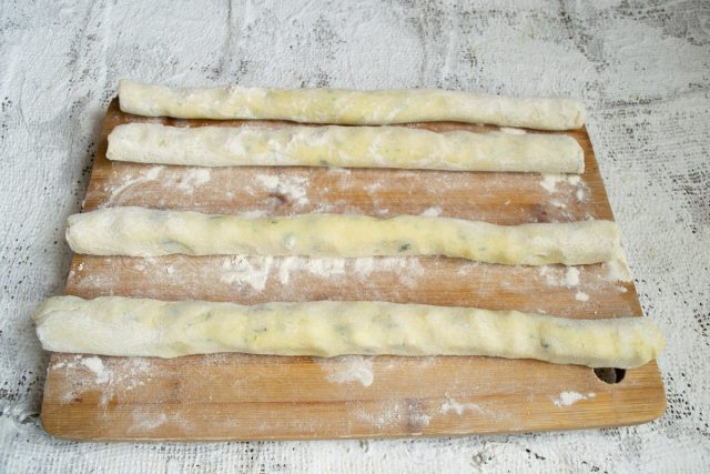 Высыпаем остаток муки на рабочую поверхность. Делим тесто на четыре равные части и скатываем из каждой длинные колбаски толщиной в пару сантиметров.
