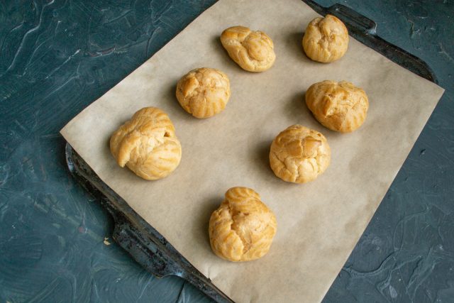 Выпекаем изделия 15 минут при 200 градусах, затем снижаем нагрев до 180 и сушим еще 20 минут. Полностью остужаем готовые профитроли перед нарезкой.