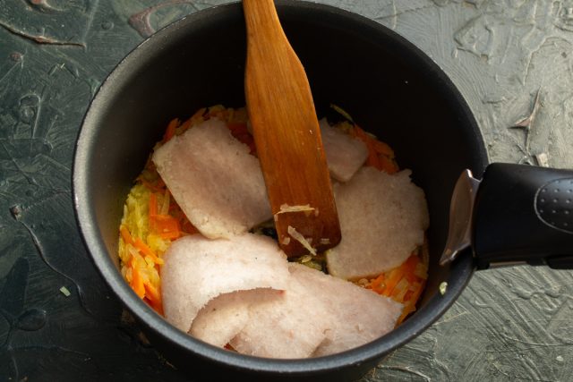 Режем рыбный фарш пластинками и выкладываем к пассерованным овощам.