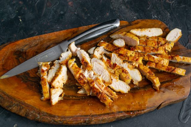 Берем отдохнувшее куриное филе и острым ножом нарезаем его тонкими ломтиками поперек волокон.