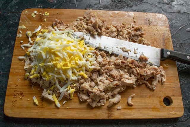 Очищаем сваренные вкрутую яйца и добавляем их к куриному филе. Измельчаем ножом мясо вместе с яйцами, чтобы получить однородную рассыпчатую массу. Очищаем сваренные вкрутую яйца и добавляем их к куриному филе. Измельчаем ножом мясо вместе с яйцами, чтобы получить однородную рассыпчатую массу.