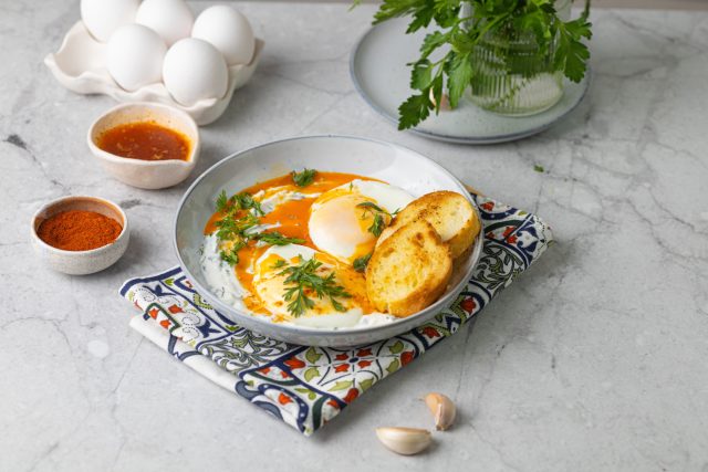 Чылбыр по-турецки — это яйца пашот на густом чесночном йогурте с ярким сливочным маслом и паприкой сверху. Контраст холодного, горячего, сливочного и острого делает блюдо очень живым и выразительным.