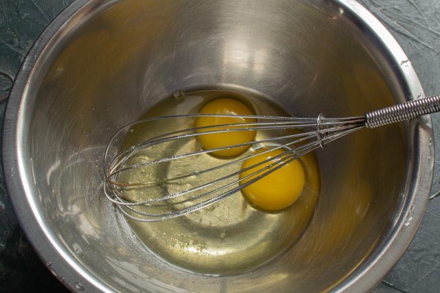 Разбиваем сырые яйца в миску, добавляем соль и сахар. Тщательно перемешиваем массу венчиком до однородности, разрушая структуру яиц без взбивания в пену.