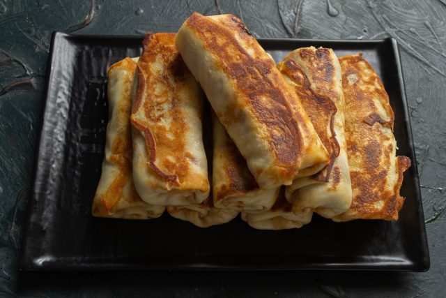 Подаем горячие блинчики с тушенкой к столу, дополнив их сметаной или соусом бешамель. Десерт или основное блюдо подается сразу после финальной обжарки.