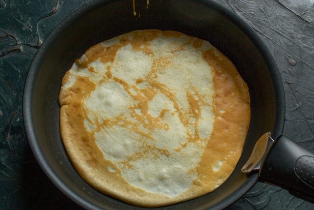 Смазываем разогретую сковороду тонким слоем масла. Наливаем порцию теста, распределяем его ровным слоем и жарим блины на сильном огне до золотистого цвета.