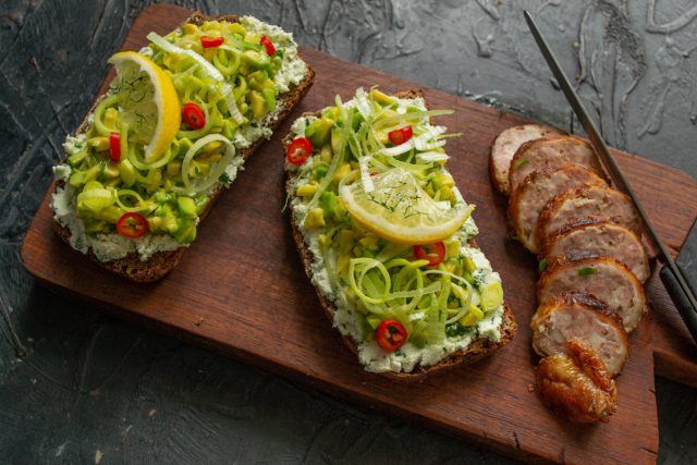 Добавляем к подаче несколько ломтиков домашней ветчины или колбаски. Сервируем готовый полезный завтрак и подаем бутерброды на стол сразу после сборки.