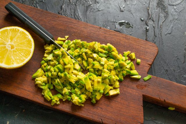 Очищаем авокадо от кожицы, извлекаем косточку и режем мякоть мелкими кубиками. Поливаем нарезку столовой ложкой лимонного сока, чтобы авокадо не темнело.