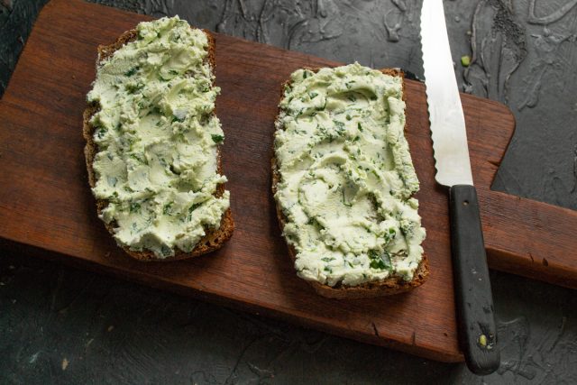 Намазываем готовую творожную пасту на ломтики ржаного хлеба. Формируем по краю небольшой бортик из сыра, чтобы удержать слой авокадо на поверхности хлеба.