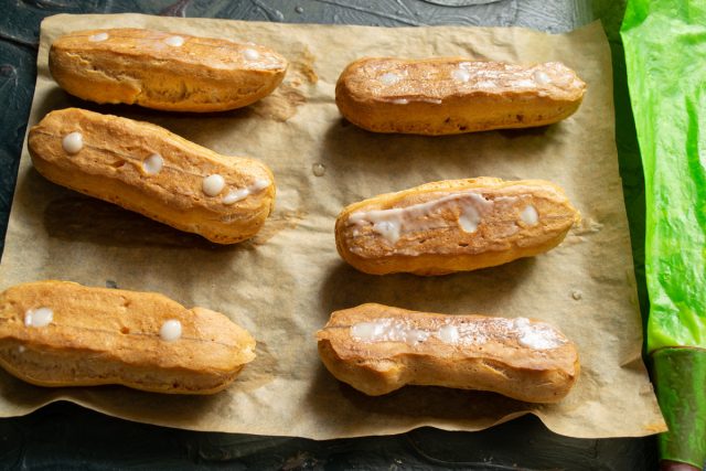 Кондитерский мешок наполняется охлажденным кремом, начинка плотно распределяется внутри каждого пирожного через подготовленные проколы до полного заполнения пустот.