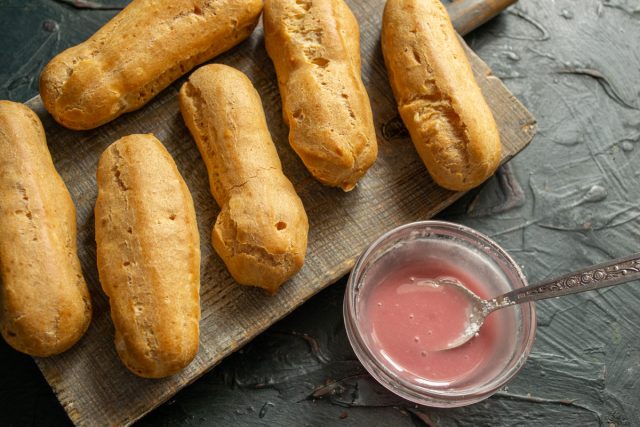 Поверхность наполненных эклеров покрывается слоем ягодной глазури и декорируется кондитерской вермишелью до момента застывания сахарной массы на воздухе.