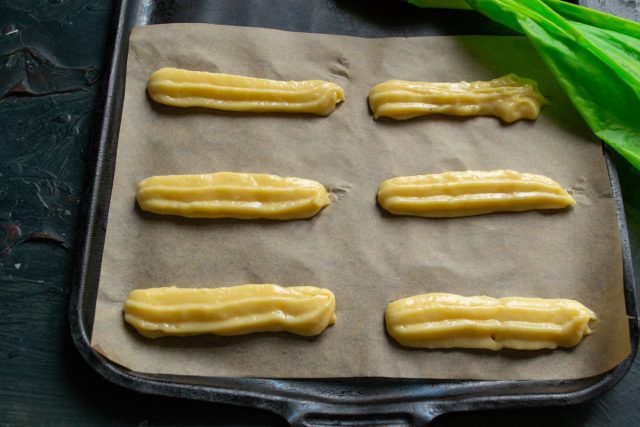 Тесто выдавливается из кондитерского мешка строго по разметке, формируя ровные заготовки одинаковой толщины для равномерного пропекания в духовом шкафу.