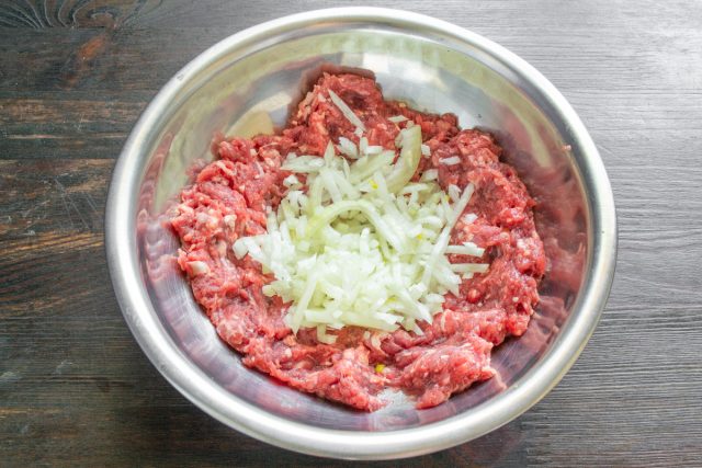 Нарезаем луковицу мелкими кубиками. Соединяем одну половину измельченного лука с охлажденным говяжьим фаршем в глубокой миске для равномерного распределения вкуса.