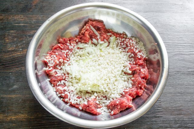 Промываем круглый рис в холодной воде несколько раз, пока жидкость не станет прозрачной. Добавляем чистую крупу к мясному фаршу и перемешиваем ингредиенты ложкой.
