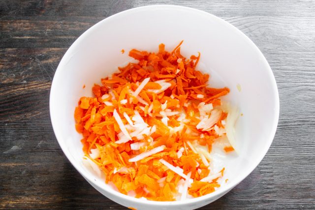 Натираем морковь на крупной терке. Смазываем форму маслом, выкладываем на дно остатки лука и тертую морковь, создавая овощную подушку для защиты от пригорания.