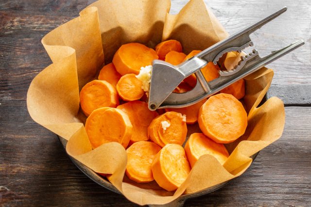 Очищаем зубчики чеснока и пропускаем их через специальный пресс прямо в сковороду к овощам. Чесночный сок пропитает мякоть батата в процессе термической обработки. Очищаем зубчики чеснока и пропускаем их через специальный пресс прямо в сковороду к овощам. Чесночный сок пропитает мякоть батата в процессе термической обработки.