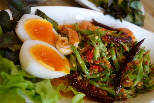 Аппетитное блюдо из четырехкрыльника пурпурного с креветками и яйцом всмятку на тарелке