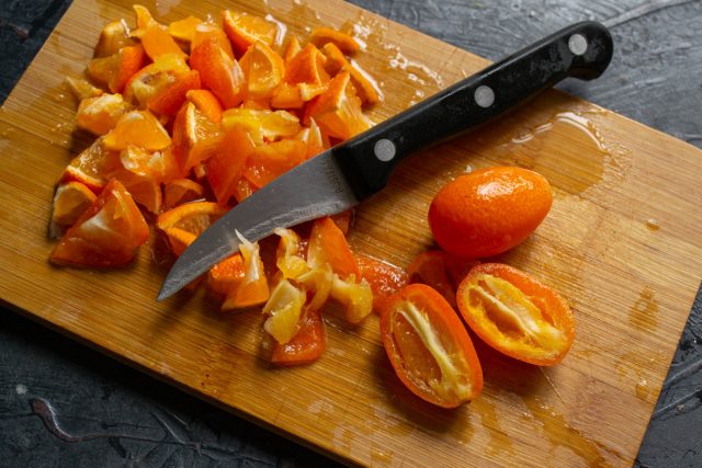 Нарезка свежих кумкватов и мандаринов на доске