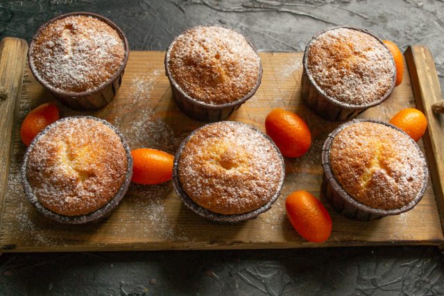 Украшение готовых кексов сахарной пудрой на тарелке