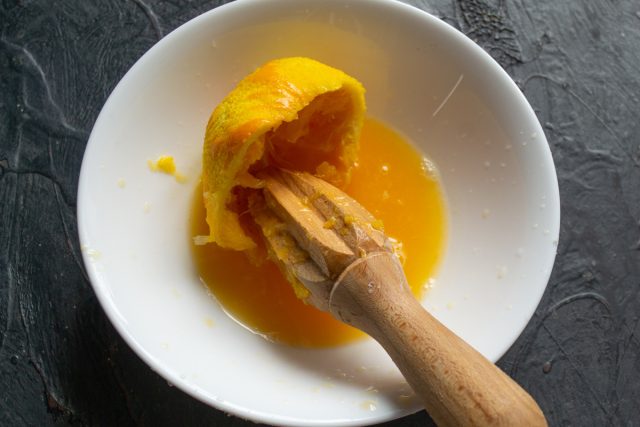 Выжимание сока из свежего апельсина в емкость