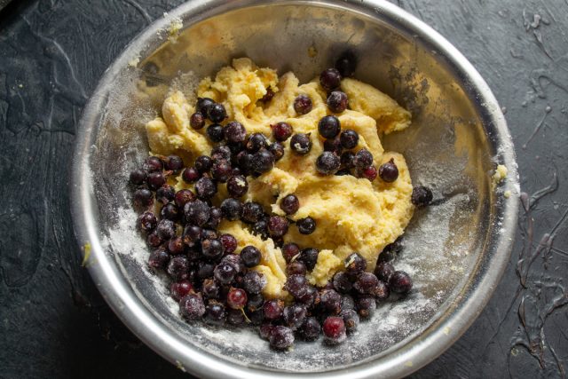 Вмешивание ягод замороженной черной смородины в тесто