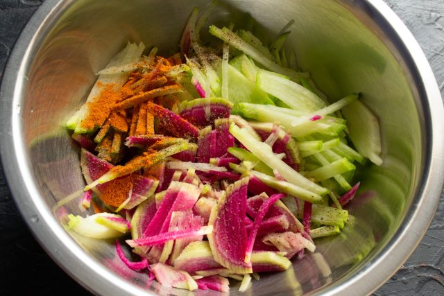 Добавление молотого красного и черного перца в миску с редькой