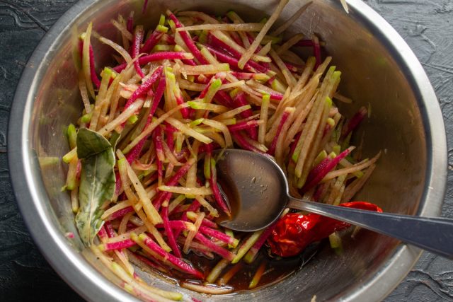 Заливка нашинкованной редьки горячим пряным маринадом в миске