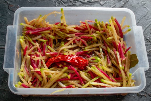 Салат из редьки в герметичном контейнере обернутом пищевой пленкой