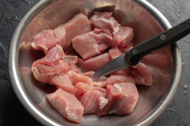 Нарезка свежей свинины средними кусочками 