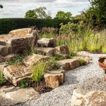 Композиции с камнем идеально ложатся на песчаные почвы: они не требуют сложного дренажа, устойчивы и легко вписываются в рельеф. Гравий, валуны и сухие цветники создают выразительное пространство без лишнего ухода.