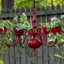 Старая люстра легко превращается в подвесное кашпо: достаточно закрепить горшки и высадить неприхотливые растения. Такой вертикальный акцент добавляет саду характер и собирает внимание, не занимая место на земле.