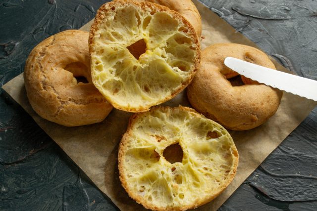 Разрезаем каждое остывшее кольцо острым ножом горизонтально на две равные части, подготавливая внутренние полости для наполнения сладкой творожной и ягодной начинкой. Разрезание остывшего заварного кольца вдоль пополам