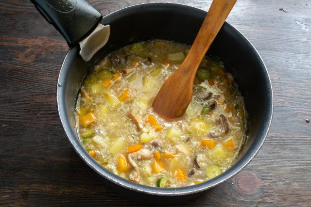 Кипящий грибной суп с киноа и картофелем варится под закрытой крышкой