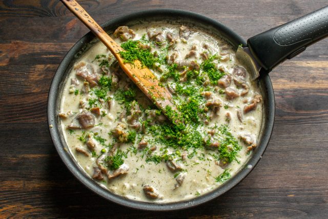 Мелко нарезанный укроп всыпается в сковороду с тушеным мясом