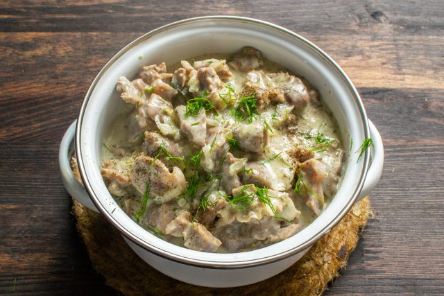 Готовое блюдо из куриных желудков в соусе подается в тарелке