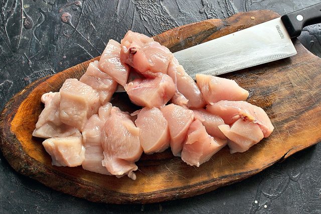 Нарезанное кубиками филе куриной грудки на доске