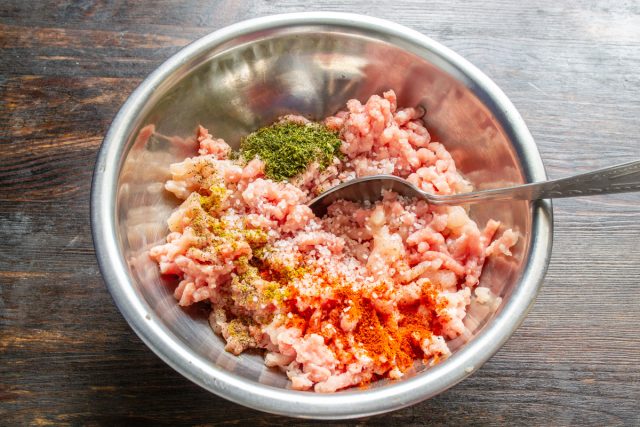 Насыпаем к готовому мясному фаршу соль, черный молотый перец по вкусу, добавляем сладкую паприку, сушеный укроп, хмели-сунели и вымешиваем массу несколько минут. Насыпаем к готовому мясному фаршу соль, черный молотый перец по вкусу, добавляем сладкую паприку, сушеный укроп, хмели-сунели и вымешиваем массу несколько минут.