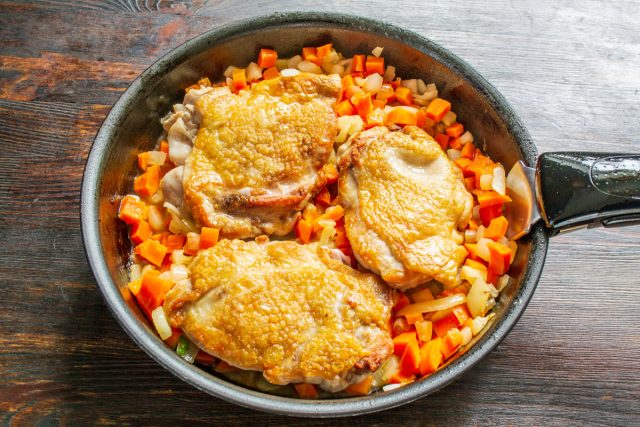 Тушение курицы с луком и морковью. Жареные куриные бедра возвращают в сковороду к обжаренным овощам.