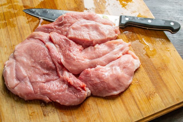 Свинину аккуратно нарезаем кусочками толщиной полтора сантиметра. Острым ножом срезаем пленки и жилы, оставляя лишь тонкие полоски жира, чтобы готовое мясо получилось сочным.