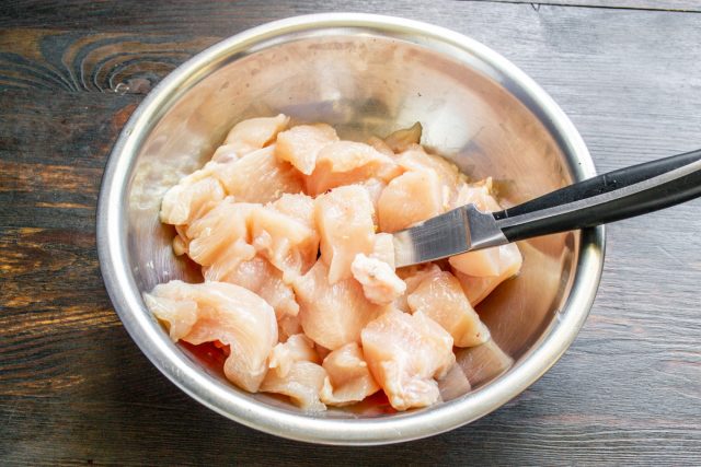 Снимаем кожу с куриной грудки и срезаем мясо с костей, после чего аккуратно нарезаем подготовленное филе аккуратными небольшими кубиками для дальнейшего фарша.