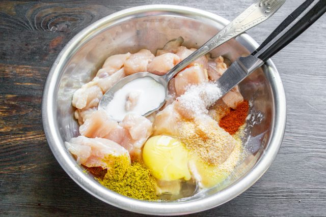 Добавляем к кубикам куриного филе яйцо, молоко, масло, а также насыпаем соль, чесночный порошок, сухую куриную приправу и ароматную молотую сладкую паприку.