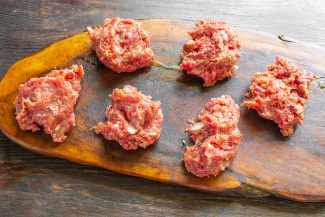 Достаем охлажденную мясную массу и аккуратно разделяем фарш на шесть абсолютно равных небольших порций для удобного формирования аккуратных праздничных закусок. Достаем охлажденную мясную массу и аккуратно разделяем фарш на шесть абсолютно равных небольших порций для удобного формирования аккуратных праздничных закусок.